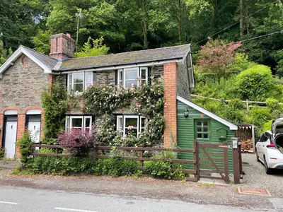 a green house with a fence in front of it at 200 year old Gardener's cottage, Mid Wales in Llanidloes