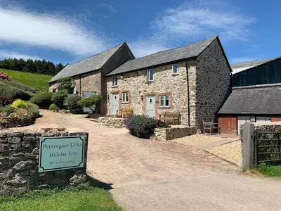 a stone house with a sign in front of it at The Barn at Pentregaer Ucha, with tennis court and lake in Oswestry