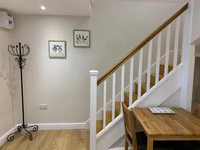 a dining room with a table and a stair case at The Barn at Pentregaer Ucha, with tennis court and lake in Oswestry