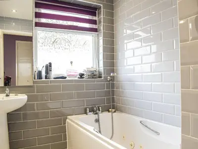 a bathroom with a tub and a sink and a window at Rhiw Gam in Abbey-Cwmhir