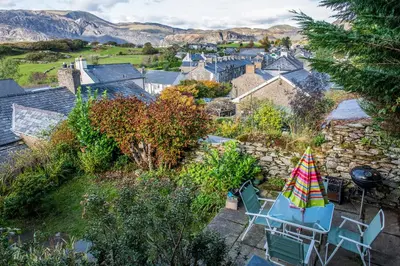 a patio with a table and chairs and a umbrella at Homely cottage with garden and mountain-view in Blaenau-Ffestiniog
