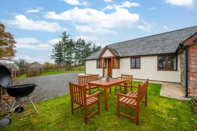 a patio with a table and chairs and a grill at 2 Bed in Y Drenewydd oc-waa402 in Llanllugan