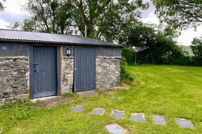 a stone building with a blue door in a field at 3 Bed in Machynlleth oc-bow306 in Darowen