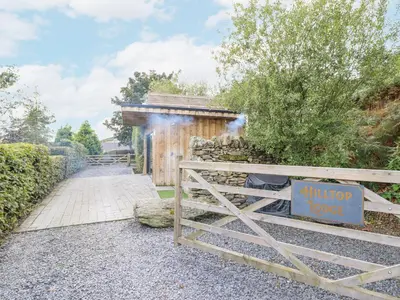 a wooden fence with a sign on it next to a building at Hilltop Lodge in Corwen