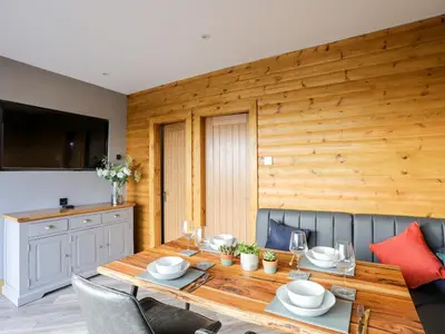 a dining room with a wooden table and chairs at Hilltop Lodge in Corwen