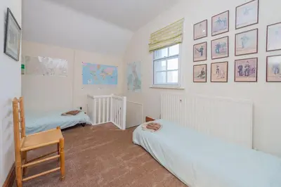 a bedroom with two beds and a chair and a window at Kwerky Cottage in North Lydbury