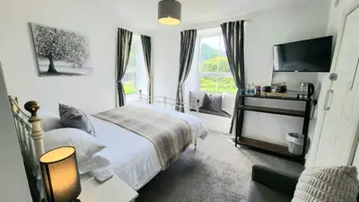 a bedroom with a bed and a tv and a window at The Queens Hotel Harlech in Harlech