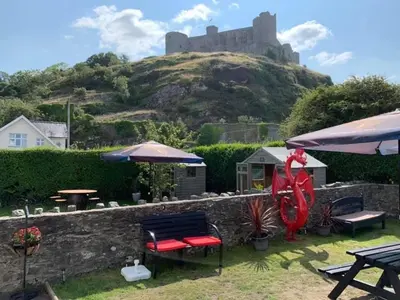 a garden with a castle on top of a hill at The Queens Hotel Harlech in Harlech