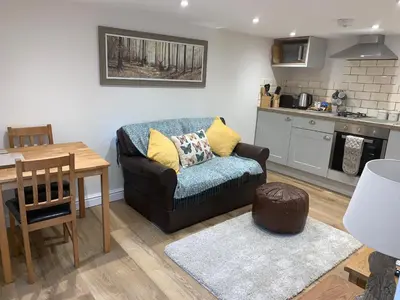 a living room with a couch and a kitchen at The Stables at Pentregaer Ucha, tennis court & lake in Oswestry