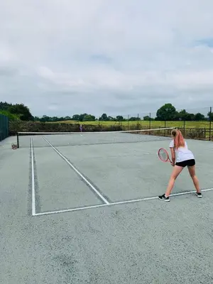 a woman playing tennis on a tennis court at The Stables at Pentregaer Ucha, tennis court & lake in Oswestry