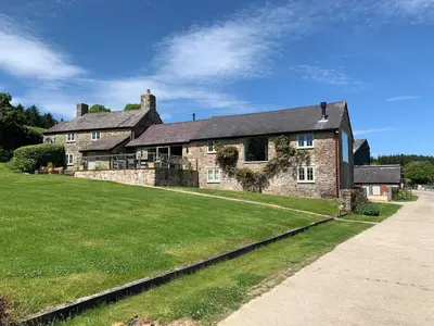 a large brick house with a large grass yard at The Stables at Pentregaer Ucha, tennis court & lake in Oswestry