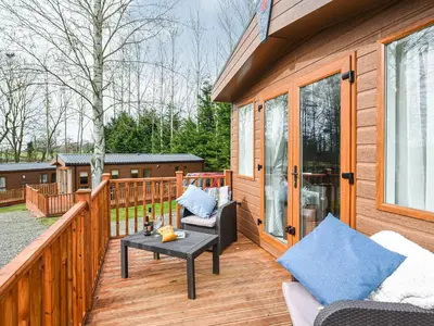a wooden deck with a chair and a table at Avon Lodge in Hyssington