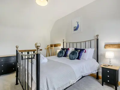 a bedroom with a bed with blue pillows at Penshenkin Barn in Llanfihangel-nant-Melan