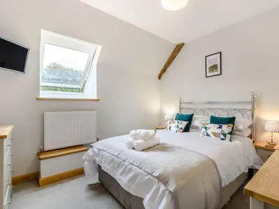 a bedroom with a large bed and a window at Penshenkin Barn in Llanfihangel-nant-Melan