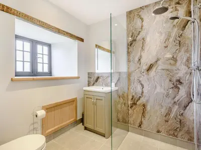 a bathroom with a shower and a toilet and a sink at Penshenkin Barn in Llanfihangel-nant-Melan