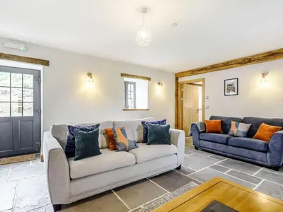 a living room with a couch and a tv at Penshenkin Barn in Llanfihangel-nant-Melan