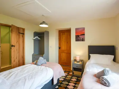 a bedroom with two beds and a window at Yr Hen Feudy At Pentre Farm in Llansilin