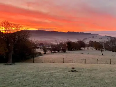 a sunset in a field with a birdbath in the foreground at Yr Hen Feudy At Pentre Farm in Llansilin