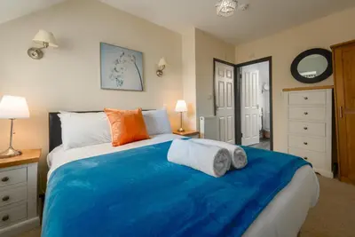 a bedroom with a blue bed with two towels on it at The Granary, Bryncarnedd cottages in Aberystwyth