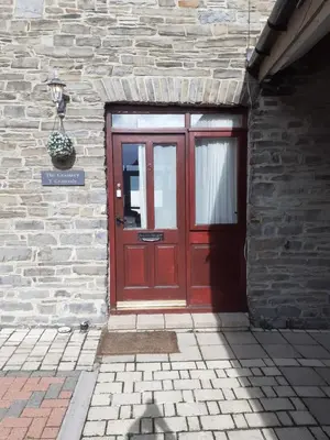 a red door on a brick building with a potted plant at The Granary, Bryncarnedd cottages in Aberystwyth