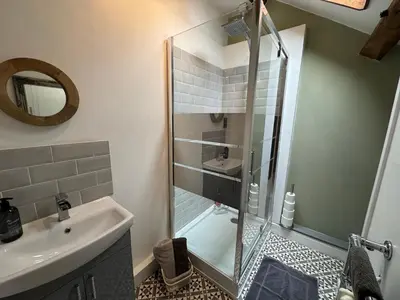 a bathroom with a shower and a sink and a mirror at Abbey Cottage in Llangollen