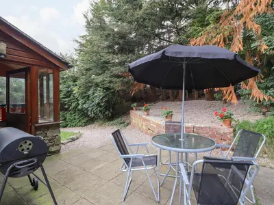a table and chairs with an umbrella on a patio at Yr Hen Felin in Oswestry