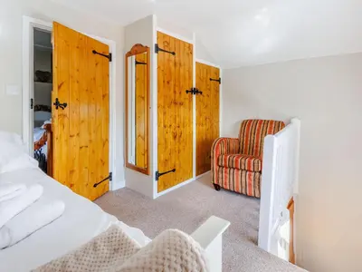 a bedroom with a bed and a chair at Elsie's Cottage in Pontesbury