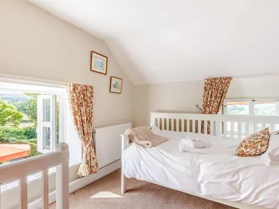a white bedroom with a crib and a window at Elsie's Cottage in Pontesbury