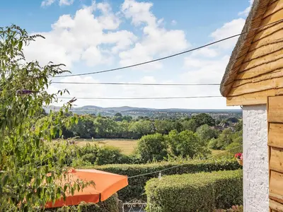 a view from the porch of a house with an orange umbrella at Elsie's Cottage in Pontesbury
