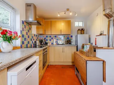 a kitchen with wooden cabinets and a white refrigerator at Elsie's Cottage in Pontesbury