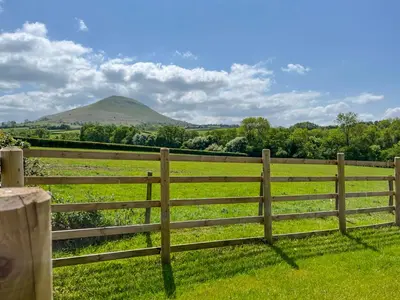 a fence in a field with a mountain in the background at Gwrlodde in Talgarth