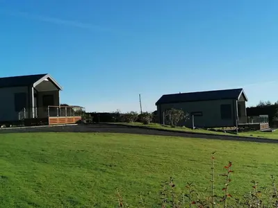 two buildings in a field with a green field at Lake Vyrnwy Luxury Glamping Pod 2 in Llanwddyn