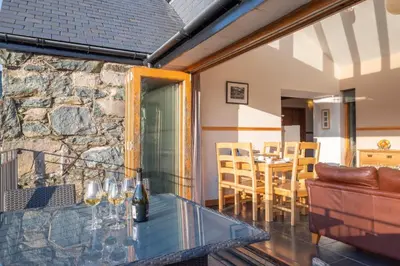 a living room with a glass table and a stone wall at 2 Bed in Dolgellau oc-bow284 in Trawsfynydd