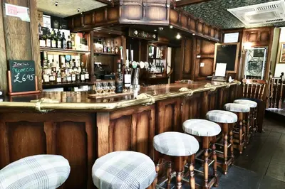 a bar with a row of stools in a restaurant at The Buckley Arms in Dinas Mawddwy