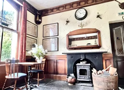 a living room with a fireplace and a clock on the wall at The Buckley Arms in Dinas Mawddwy