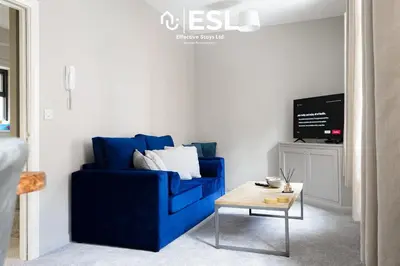 a blue couch in a living room with a table at Comfy Modern 2 Bedroom Duplex Apartment with Sun Terrace in Shrewsbury
