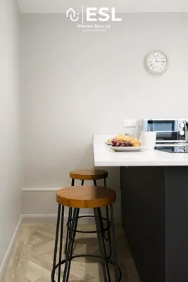 a kitchen with two stools and a plate of food on a counter at Comfy Modern 2 Bedroom Duplex Apartment with Sun Terrace in Shrewsbury