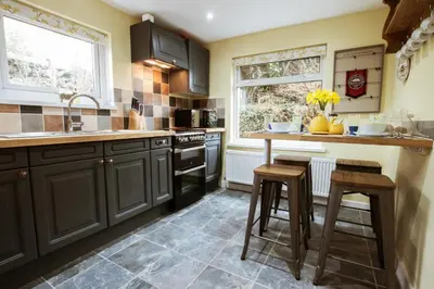 a kitchen with black cabinets and a counter and stools at Cosy, coastal cottage in Snowdonia in Harlech