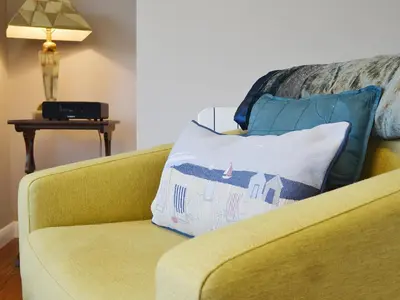 a yellow couch with a pillow on it at Seascape in Aberystwyth