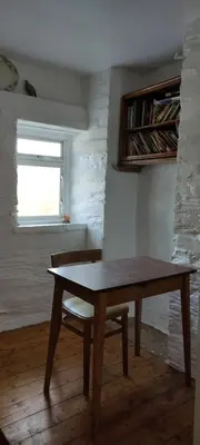 a wooden table and chair in a room with a window at Toad Hall Hostel in Machynlleth