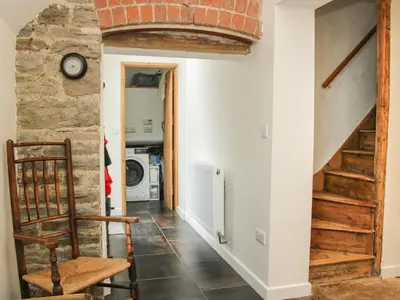 a hallway with a staircase and a brick wall at Denbigh Hall in Leominster