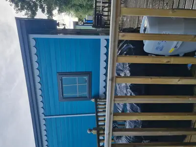 a blue shed with a ladder next to it at Glamping Hut - Riverview 3 in Welshpool