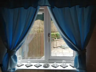 a window with wine glasses and blue curtains at 1 Park Terrace in Corris