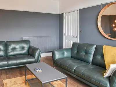 a living room with a leather couch and a table at Ty Isaf in Barmouth