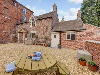 a patio with a wooden table in front of a brick building at Little Whitley - Uk38099 in Great Hanwood