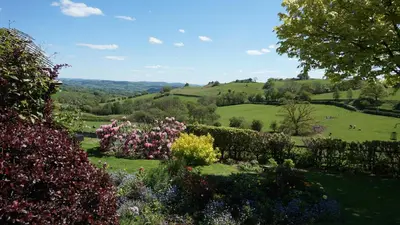 a garden with a view of the rolling hills at Sheep Dip Cottage - 5* Cyfie Farm, with log burner and private hot tub in Llanfyllin