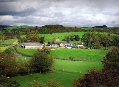 a large green field with a farm in the distance at Sheep Dip Cottage - 5* Cyfie Farm, with log burner and private hot tub in Llanfyllin