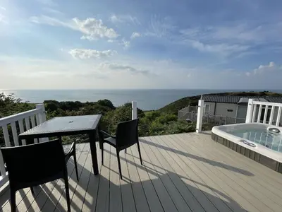 a deck with a table and chairs and a swimming pool at Sea Breeze Lodge in Aberaeron