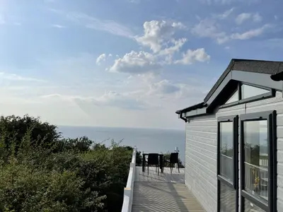 a house with a deck with a view of the ocean at Sea Breeze Lodge in Aberaeron