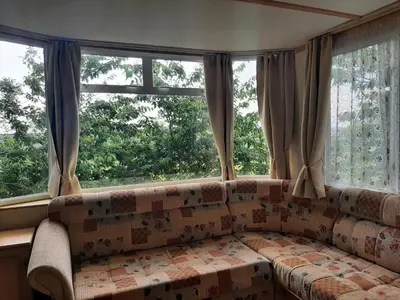 a living room with a couch and two windows at Cadwgan Caravan in Dyffryn